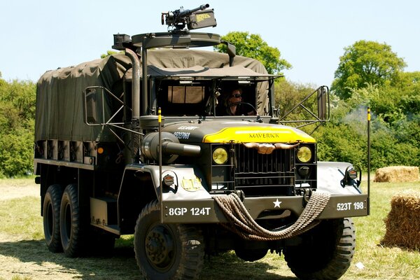 Grande camion militare con autista su sfondo di alberi verdi