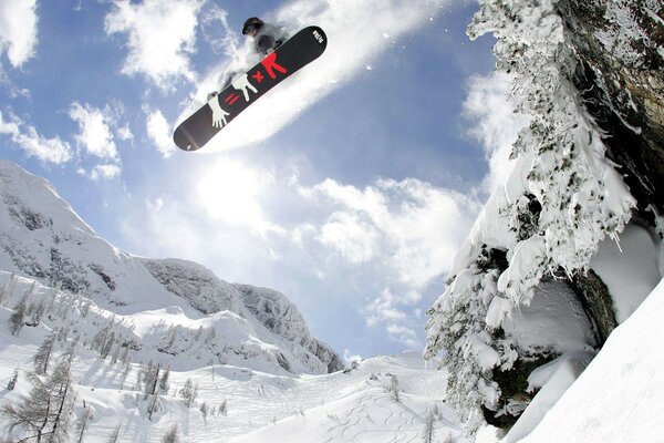 Salto de snowboard entre las montañas en invierno