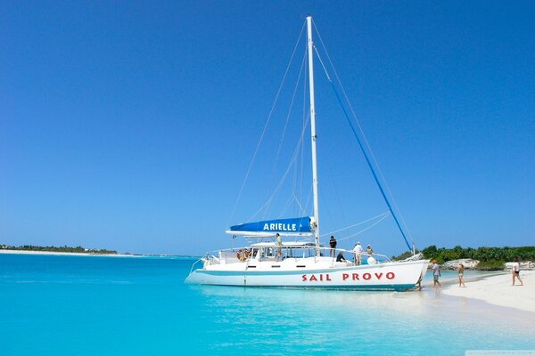 Segelboot mit Urlaubern fährt vom Strand ab