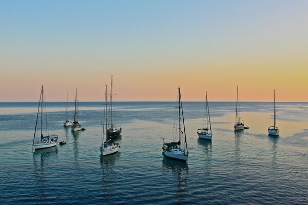 Barcos de pie en el mar durante la puesta de sol azul