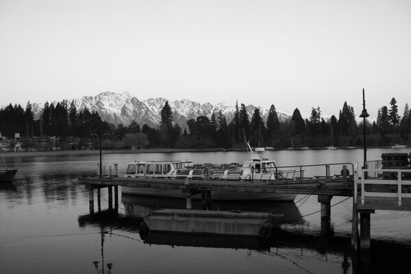 Foto en blanco y negro del barco en el fondo de las montañas