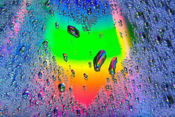 Rainbow heart behind glass with drops