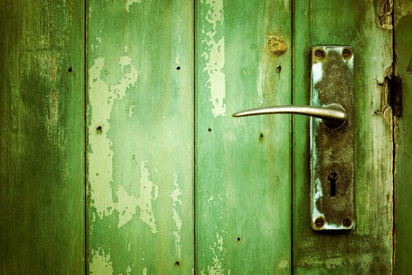 Puerta vieja de la tabla verde con la Cerradura de la puerta