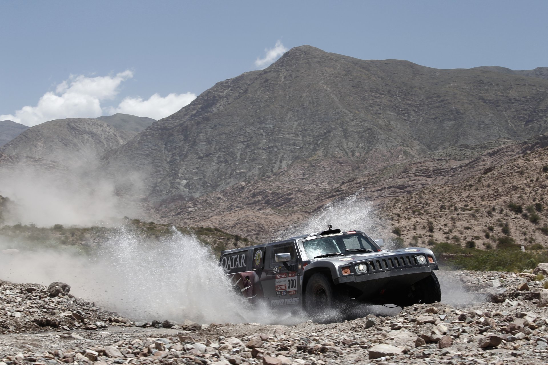 martillo dakar rally suv frente montañas cielo salpicaduras hummer