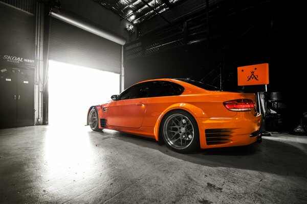 Une bmw orange se tient dans le garage