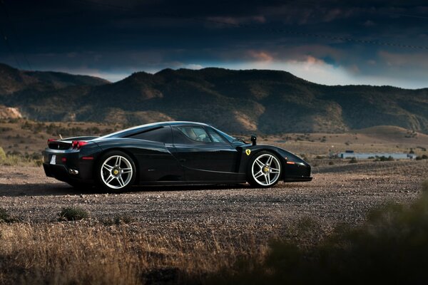 Ferrari Enzo noir sur fond de montagnes