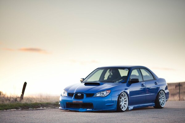 Blue Subaru suburban on the background of a clear sky at sunset