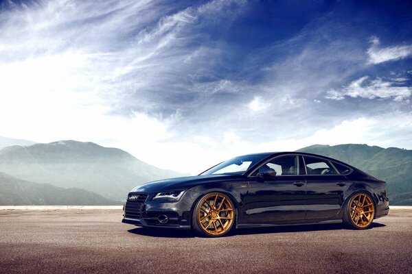 Azul audi A7 en el fondo de las montañas y el cielo vista lateral