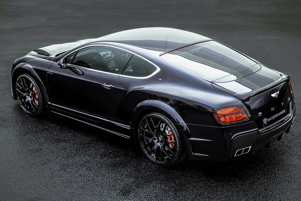 El Bentley Onyx negro se encuentra en el asfalto mojado