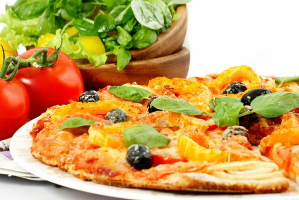 Delicious pizza and red tomatoes with greens