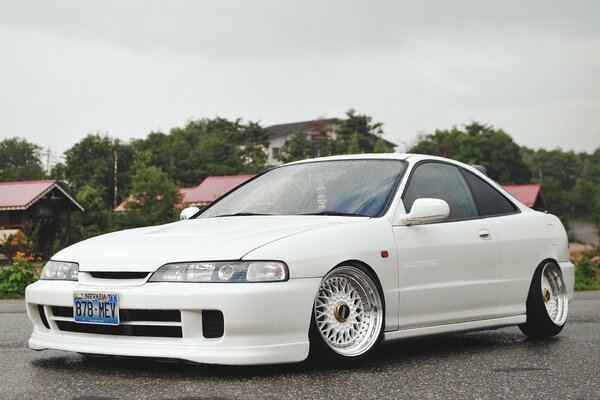 White Honda tuned, front and side view, on an asphalt road