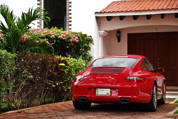 Czerwone Porsche Carrera stoi przed garażem