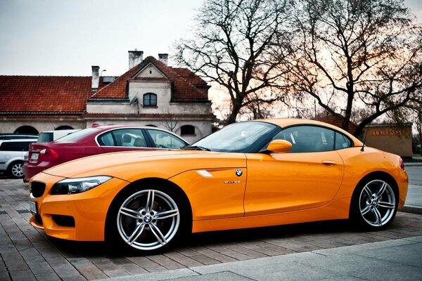 Llantas frescas de BMW naranja en el fondo de la ciudad de otoño