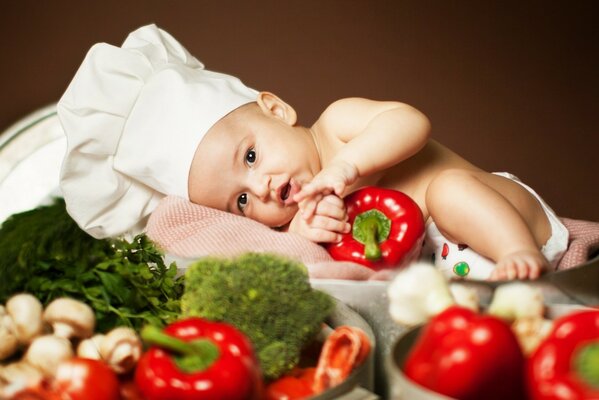 Un niño en una gorra de cocinero junto a los alimentos