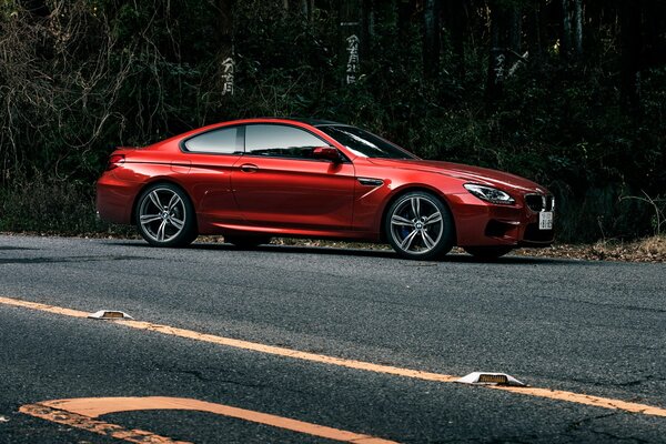 Rouge brillant BMW m6cupe sur la route à l ombre