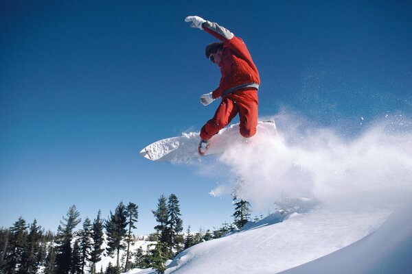 A snowboarder moves off a snowy mountain