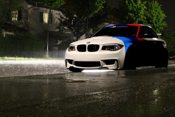 BMW rayado por la lluvia de la noche de la ciudad