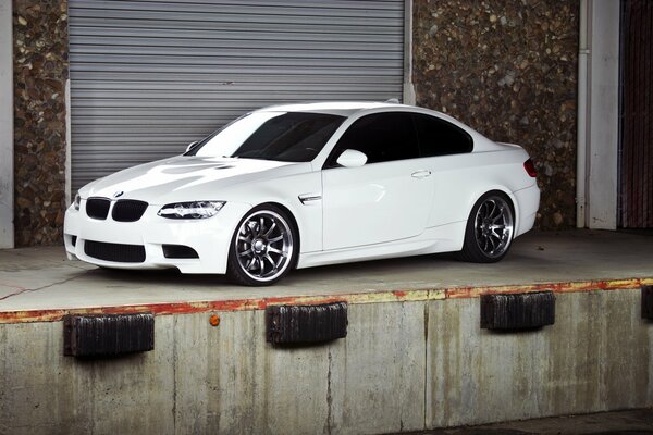 A white BMW is parked at the garage