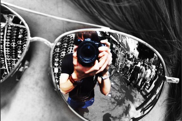 The reflection of the photographer holding the lens in the glasses of the glasses