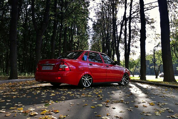 Lada rossa del Priore sulla strada con fogliame autunnale