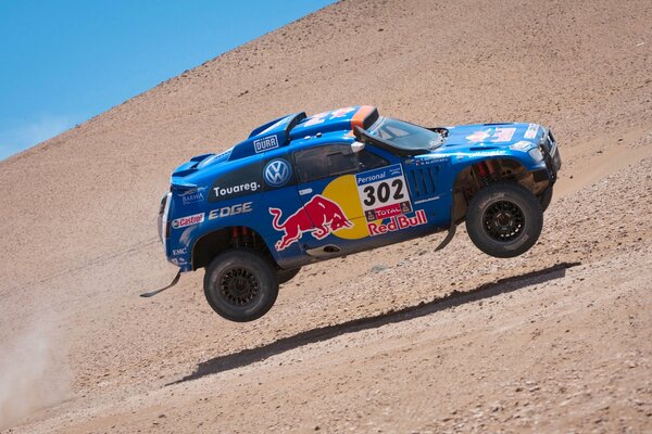 Blue Volkswagen Touareg in the air and in the desert at the rally