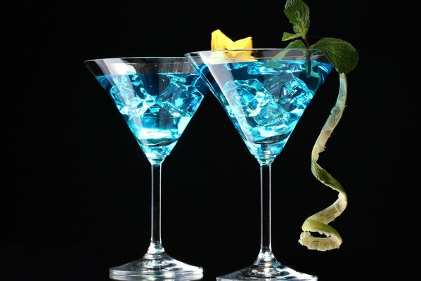 Auf schwarzem Hintergrund stehen 2 Martini-Gläser mit blauer Flüssigkeit