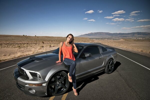 Belle fille en haut orange à côté de la Mustang Ji TI 500 dans le désert