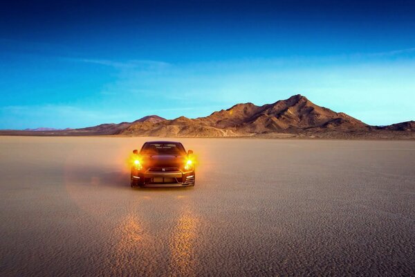 L auto brilla con i fari nel deserto