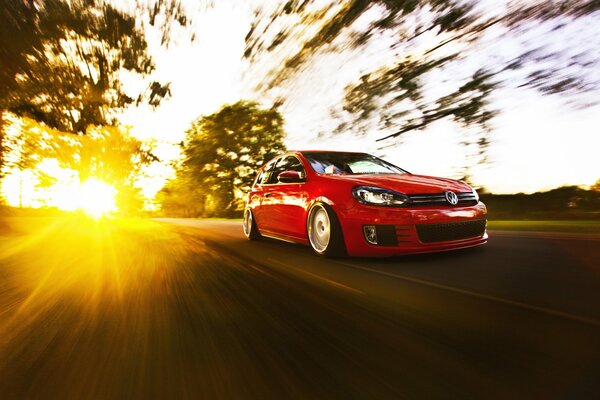 Red Volkswagen golf on the background of sunlight, in motion