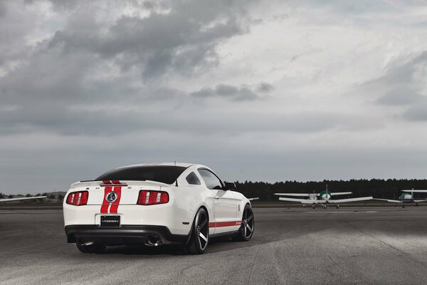 Biały Ford Mustang na pasie samolotu