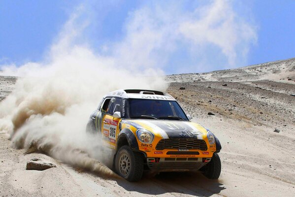 Multi-colored mini cooper rushing in sand and dust