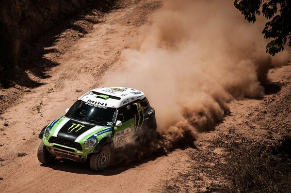 A green mini cooper at speed and clouds of dust from it