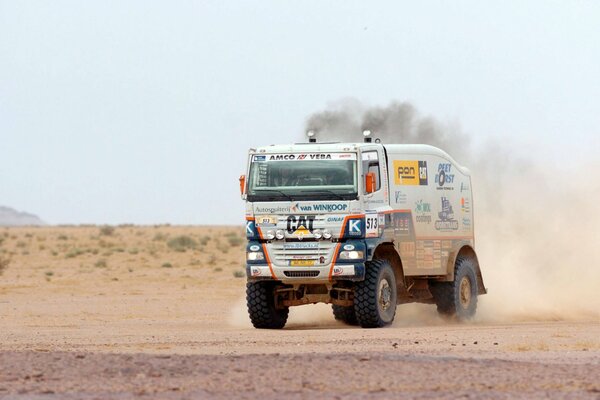 Un camión de carreras conduce a través de un poste de polvo del desierto