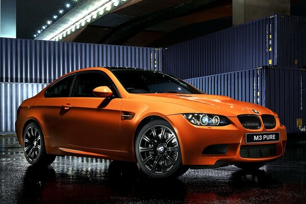 BMW orange sur fond de conteneurs sous le pont