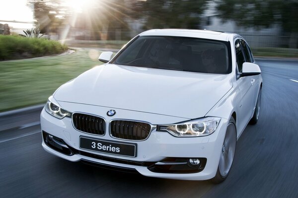 A white handsome bmw rushes along an asphalt road