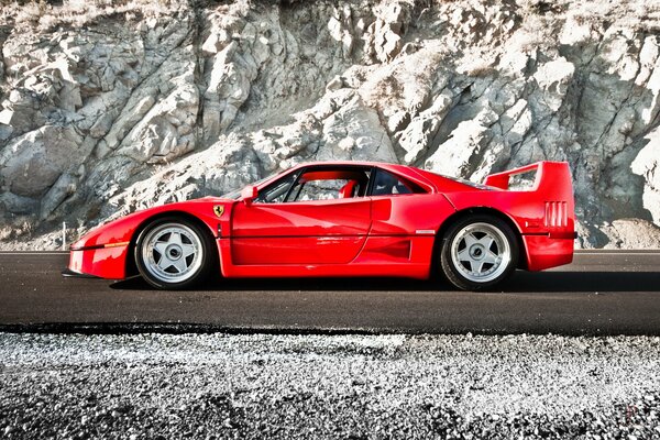 Red Ferrari sports car on the background of rocks