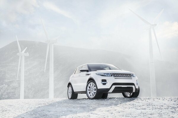 White Renge Rover su uno sfondo di turbine eoliche bianche, montagne e cielo limpido