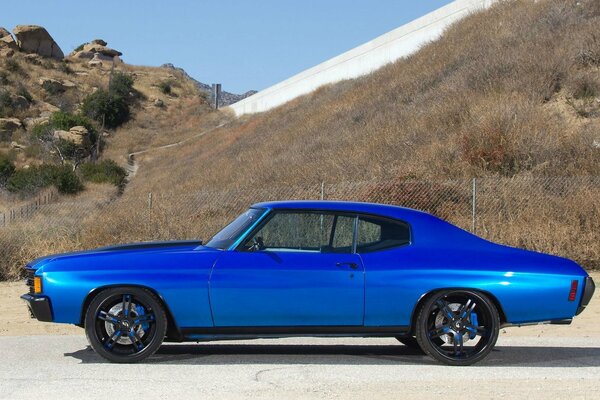 A blue 1972 car is parked in the parking lot