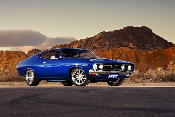 Blue Ford car on the background of mountains and cloudy sky