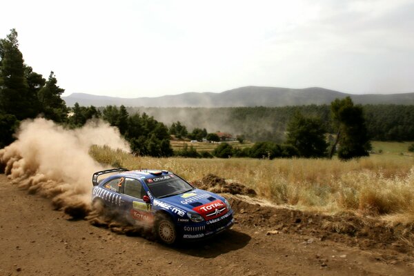 Citroen car, participating in the rally, rides on a dirt road, raising a column of dust