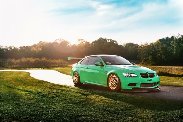 Green BMW in the glare on a sunny road