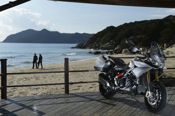 Foto de una motocicleta en la playa contra el mar y las rocas