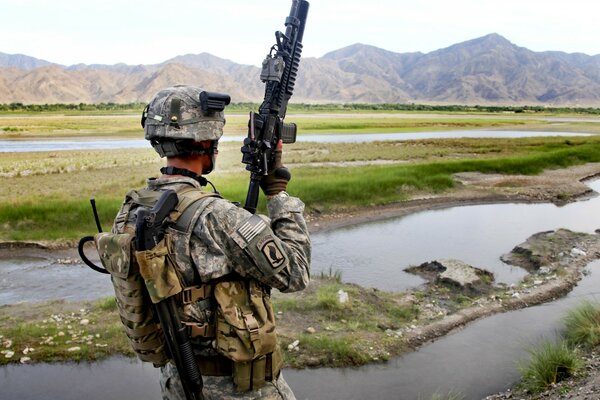 Soldado de pie con una ametralladora en el fondo del río