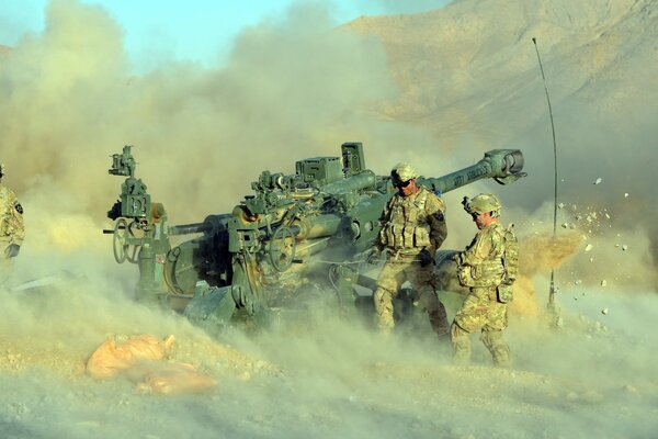 Soldaten an der Haubitze inmitten von Sand und Bergen