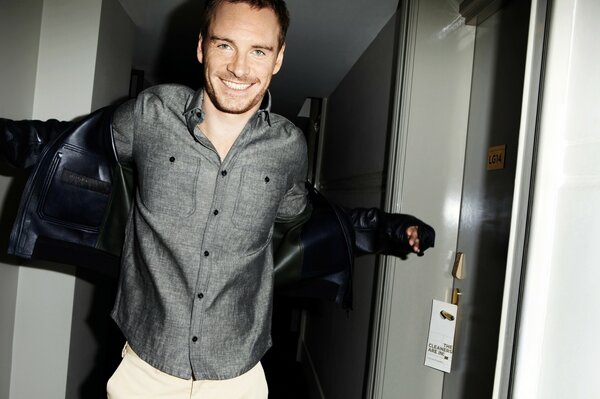 Michael Fassbender en riant dans une chemise grise