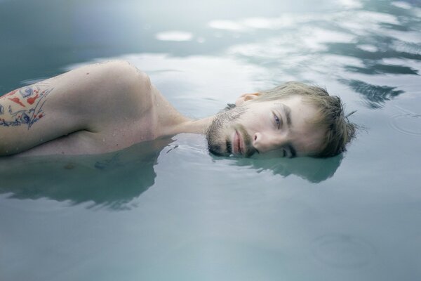 Homme couché dans l eau avec un tatouage