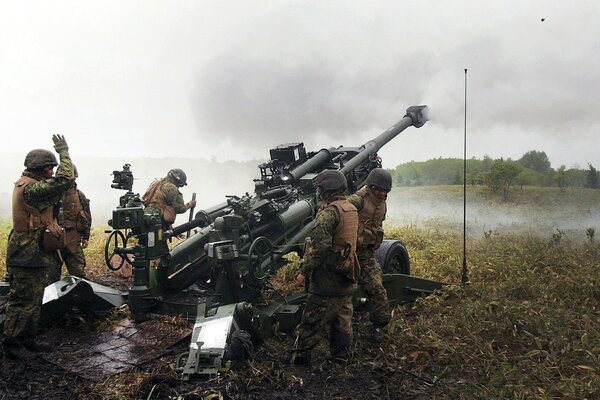 Das Militär, das aus einer Haubitze am Fluss schießt