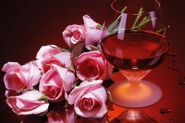 Verre de cognac sur fond rouge avec des roses