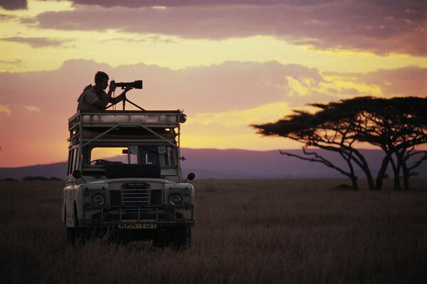 Ein Fotograf auf einem Autodach in Afrika fängt einen Rahmen ein