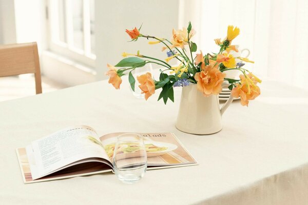 On the table there is a vase with flowers and an open book